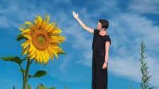 Frau neben einer lebensgroßen Sonnenblume