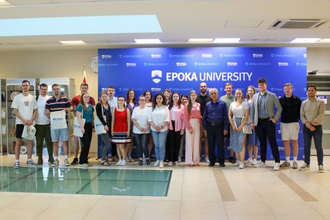 Ca. 25 Menschen, die vor einer blauen Wand stehen, auf der EPOKA UNIVERSITY steht