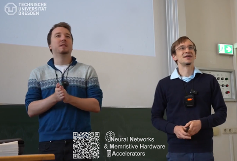 zwei Lehrpersonen stehen vorne am Pult und im Hintergrund wird eine PPP an die Wand gestrahlt