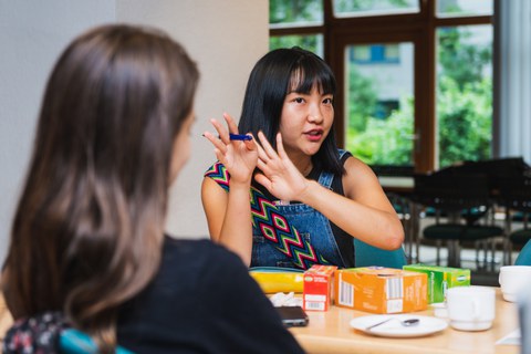 Photo of two women sitting opposite each other at a table and talking.