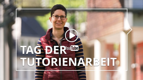 Person steht lächelnd im Freien, im Hintergrund Gebäude und Bäume. Darüber eingeblendet: „Tag der Tutorienarbeit“ mit YouTube-Symbol und Play-Button.