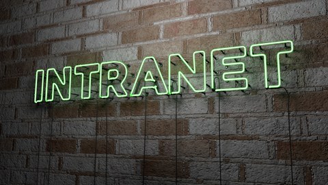 Leuchtschriftzug „INTRANET“ in grüner Neon-Schrift an einer Backsteinwand.