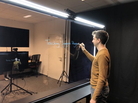 Ein mann steht vor einem Lightboard und schreibt darauf.