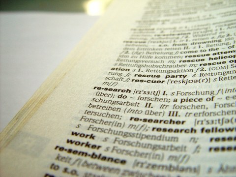 Nahaufnahme eines Wörterbuchs. Der Eintrag übersetzt das Wort "research" ins Deutsche. 