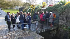 Students stand in a semicircle and listen to a man.