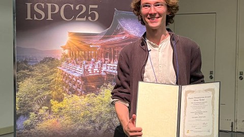 A young man holds a certificate in his hand.