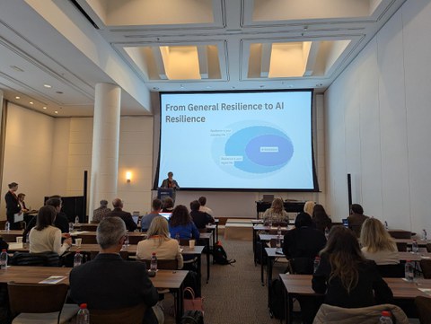 Eine Frau steht in einem großen Saal und präsentiert vor einem Publikum