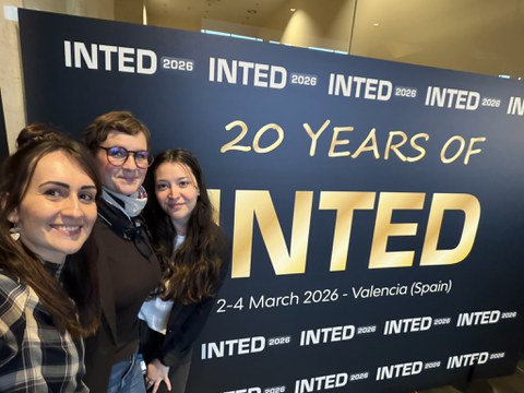 Drei Frauen machen ein Selfie vor dem INTED-Plakat