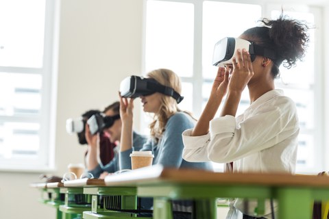 Junge Menschen sitzen in einem Raum und tragen virtual reality Brillen.