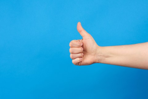 The picture shows a hand with thumbs extended upwards.