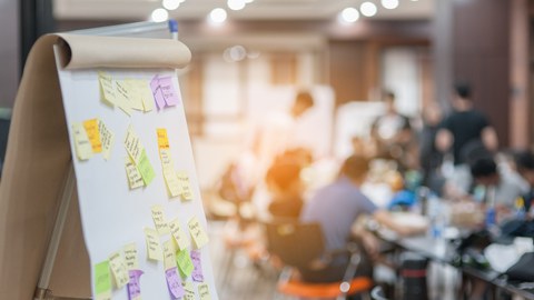 The picture shows a flipchart with different colored sticky notes. 