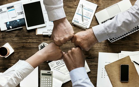 Vier Menschen strecken ihre Hände zusammen.