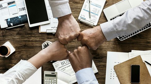 Vier Menschen strecken ihre Hände zusammen.