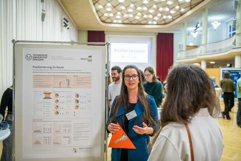 2 students talking to each other, standing next to a scientific poster