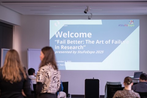 The picture shows a seminar room where a welcome slide for the event is shown.