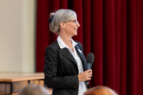 Eine Frau hält ein Mikrofon in der Hand und lacht.