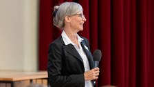 Eine Frau hält ein Mikrofon in der Hand und lacht.