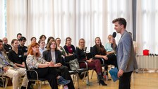 Das Publikum ist zu sehen und rechts im Bild steht der Moderator.