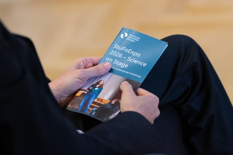 Es sind Hände zu sehen, die das Programmheft mit dem Titel "StuFoExpo 2026 - Science on Stage" halten.