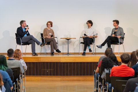 Auf der Bühne sitzen die vier Teilnehmenden des Podiumsgesprächs.