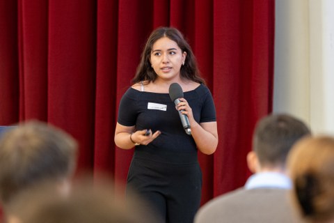 Eine Studentin hält einen Vortrag, unten im Bild ist das Publikum zu erkennen.