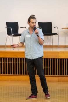 Ein Student steht vorne und spricht in ein Mikrofon.
