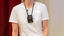 Eine Studentin steht vor einer Bühne.