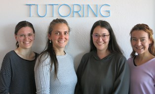 Das Team des Projekts Tutoring als Gruppenporträt (links beginnend: Beatrice Schlegel, Michelle Eichler, Melanie Ludwig, Marina Hüttich) als Halbfiguren vor Koniferenhecke