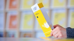 Foto zweier Hände, die einen aufgeschlagenen Gelben Flyer halten, auf dem das Logo der TU Dresden zu sehen ist