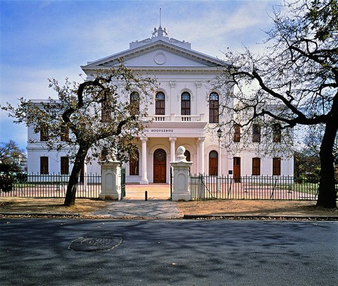 Universitätsgebäude der Stellenbosch-Universität. Weißes, schönes Haus mit Säulen und Bäumen davor. 