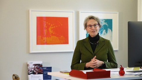 Die Rektorin Prof. Dr. Ursula Staudinger steht an einem Schreibtisch