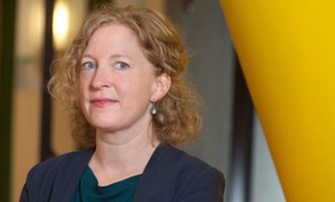 Porträtfoto von Anna Holzscheiter vor gelben und grauem Hintergrund