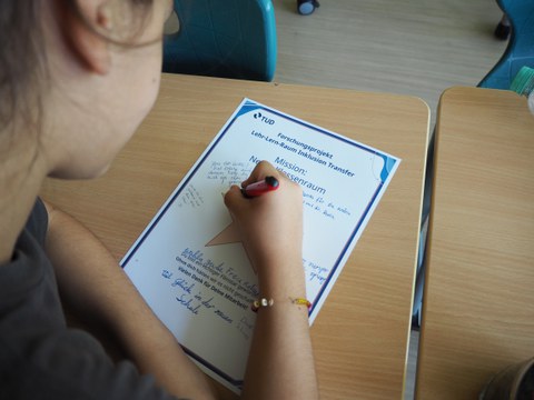 Kind schreib etwas auf einer Urkunde in Nahansicht 