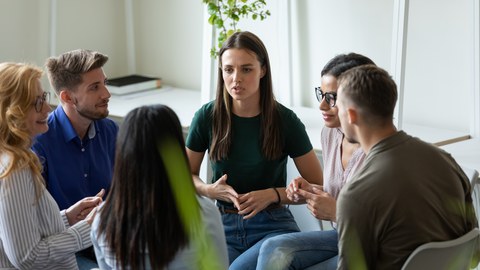 Foto: Sechs Personen sitzen sich in einem Kreis gegenüber und unterhalten sich.inem