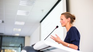 Das Foto zeigt eine junge Frau an einem Rednerpult.