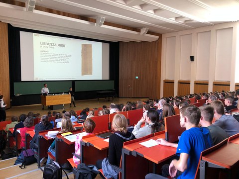 Menschengruppe sitzt in Reihen in einem Hörsaal