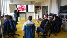 Auf dem Bild sind die Teilnehmenden des Workshops "Anforderungen an eine Befähigung auf dem Gebiet der didaktischen Medien aus der Sicht der Lehrenden" in einem Seminarraum zu sehen, die dem Dozenten zuhören.