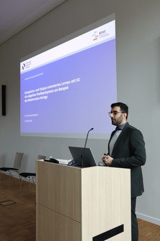 Auf dem Bild ist Dr. Sam Toorchi Roodsaari bei seiner Keynote zum Thema „Kompetenz- und outputorientiertes Lernen mit KI: ein adaptives Feedbacksystem am Beispiel des Westermann-Verlags“  zu sehen