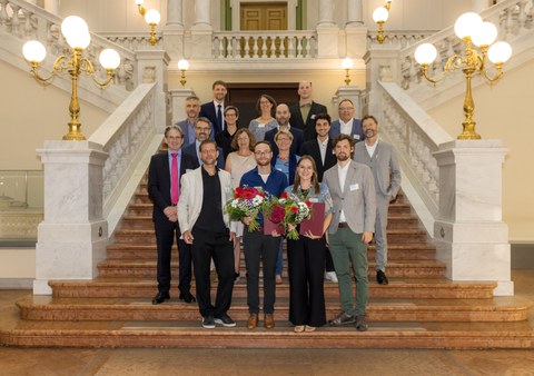 ca. 10 Personen stehen auf einer Treppe zu einer Preisverleihung. 