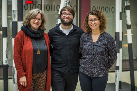 Bild einer Gruppe von 3 Personen, die in die Kamera lächeln