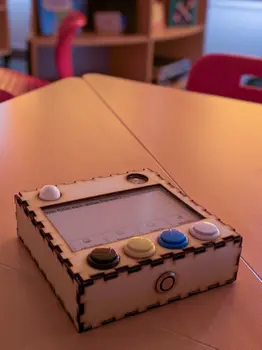 Ein kleines Gerät aus Holz, mit einem Bildschirm und haptischen Knöpfen, die bestimmte Gefühle beschreiben.