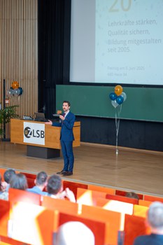 Mann hält Vortrag auf einer Bühne im Hörsaal