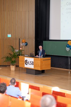 Mann hält Vortrag und steht an einem Pult