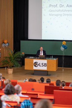 Mann hält Vortrag und steht an einem Pult
