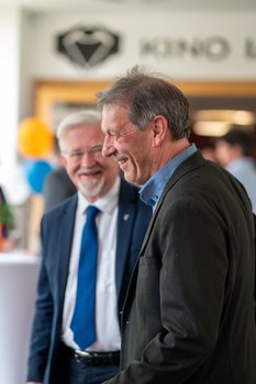 Zwei Männer unterhalten sich und lächeln dabei.
