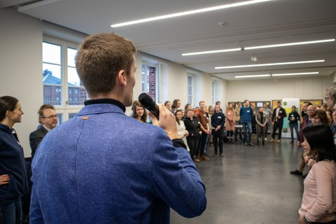 Foto zeigt einen Saal mit einem Mann, der einen Vortrag hält.