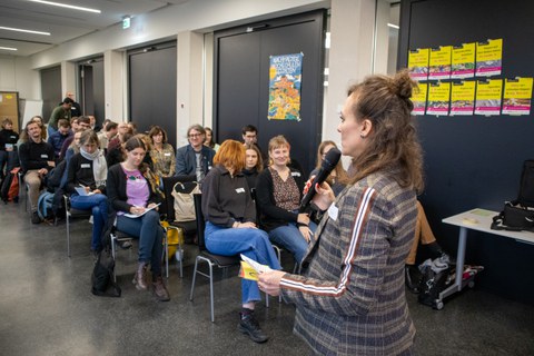 Foto zeigt einen Saal mit einer Frau, die einen Vortrag hält.