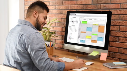 Junger Mann nutzt Kalender-App am Computer im Büro