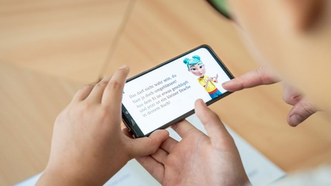 Ein Schüler hält ein Smartphone mit einer Lernapp in den Händen