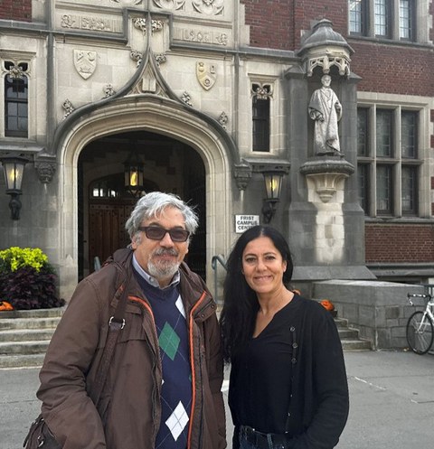 Mann und Frau stehen nebeneinander vor einem Unigebäude.